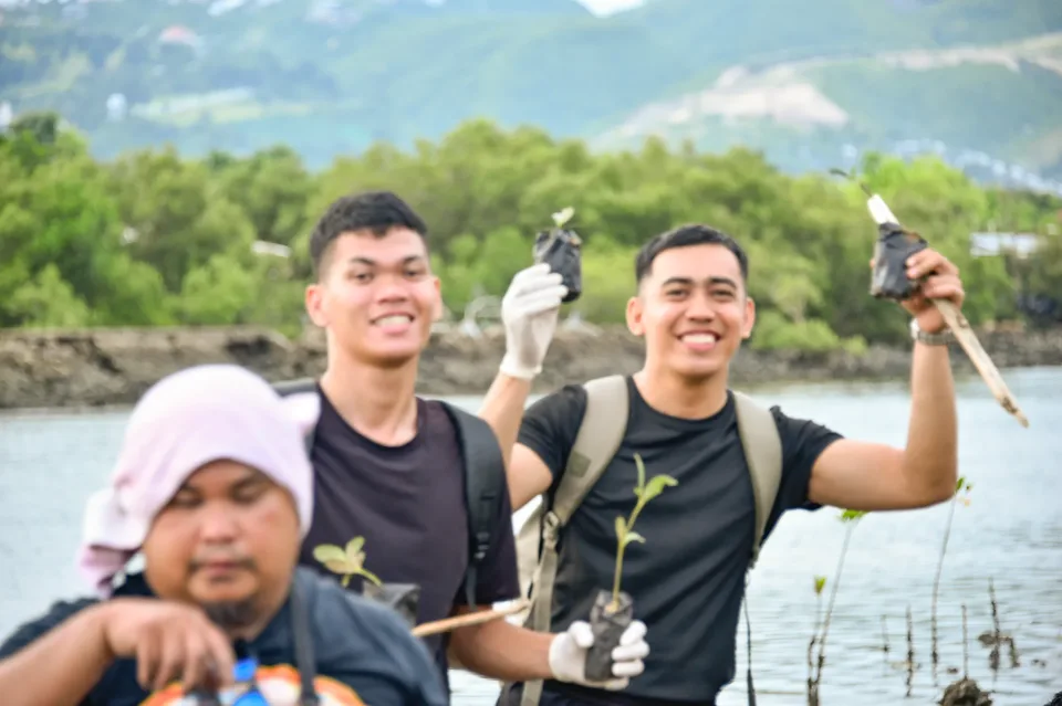 IPI employees planting mangrove propagules by hand across a tidal flat during the company’s EcoWellness mangrove planting day