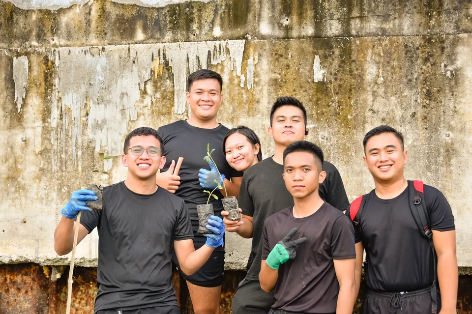 IPI employees planting mangrove propagules by hand across a tidal flat during the company’s EcoWellness mangrove planting day