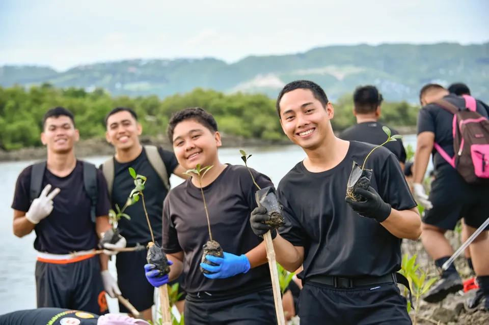 IPI employees planting mangrove propagules by hand across a tidal flat during the company’s EcoWellness mangrove planting day