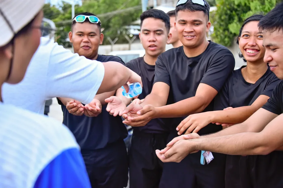 IPI employees planting mangrove propagules by hand across a tidal flat during the company’s EcoWellness mangrove planting day