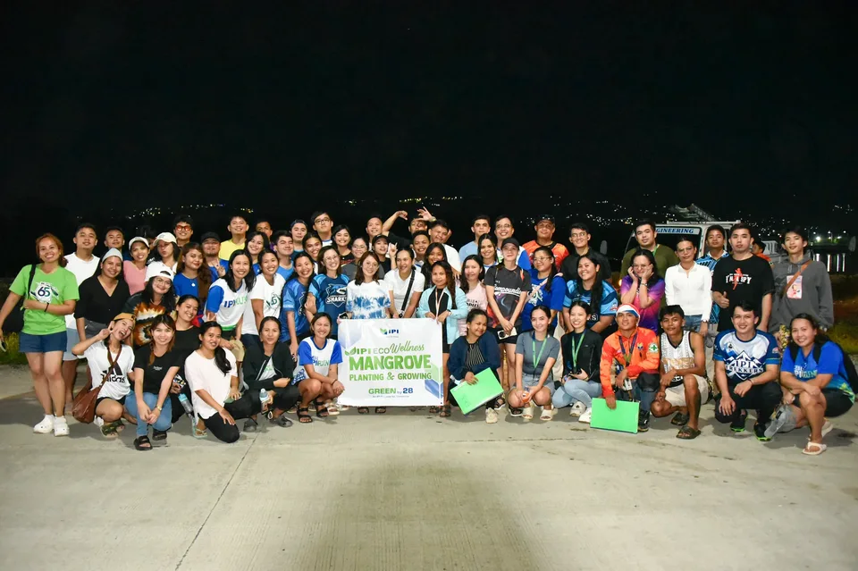 IPI employees planting mangrove propagules by hand across a tidal flat during the company’s EcoWellness mangrove planting day