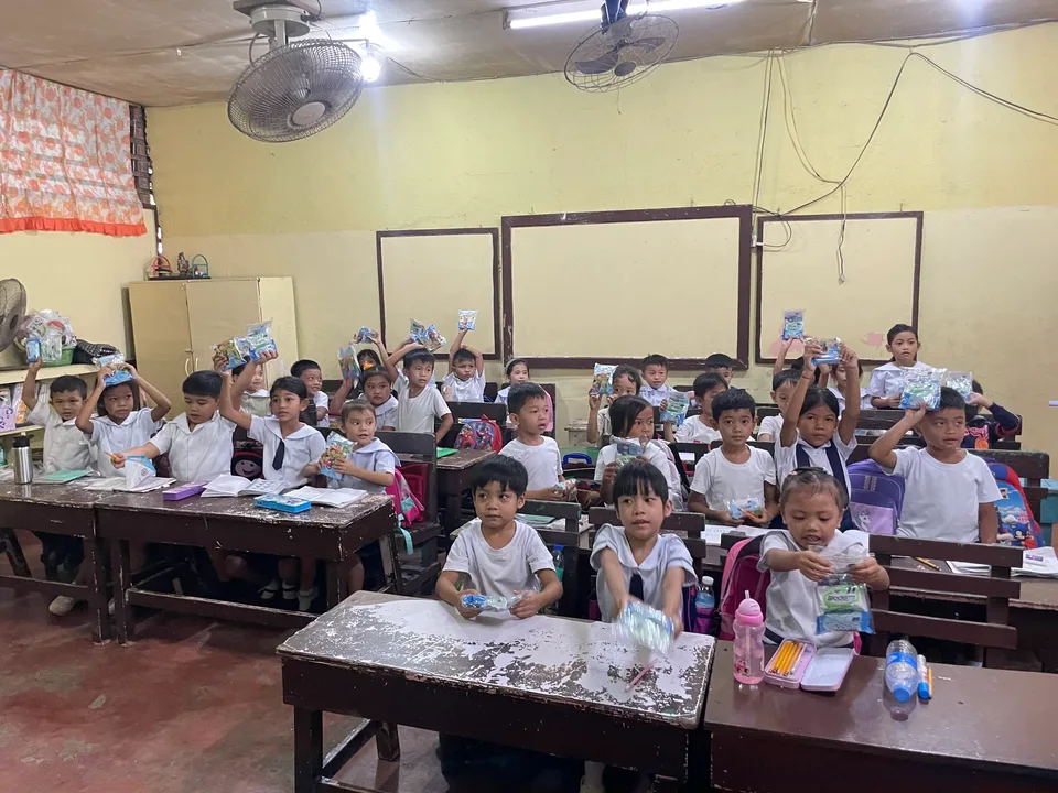 Schoolchildren in their classroom during an IPI Adopt-a-School handwashing and hygiene session, holding the hygiene kits they were given