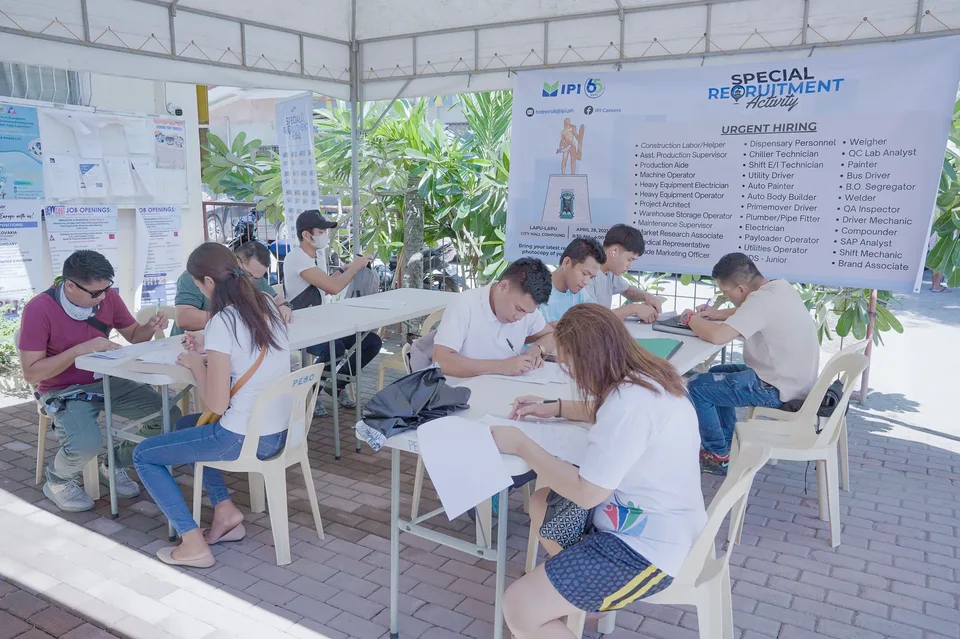 Applicants completing forms and meeting IPI recruiters at a PESO special recruitment activity held under tents in the city grounds