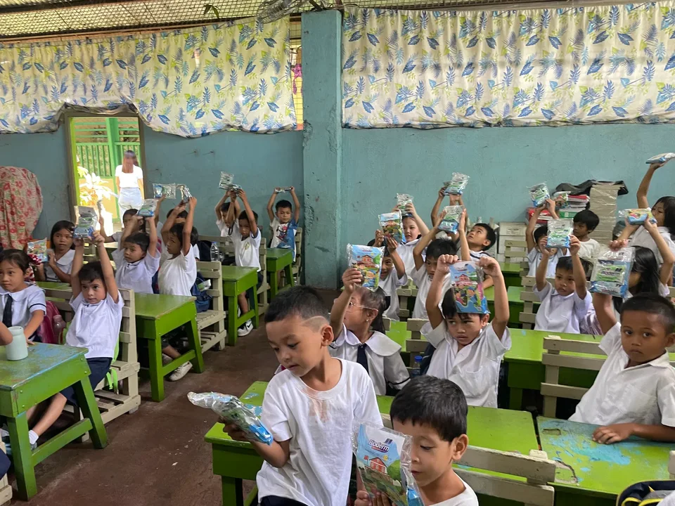 Schoolchildren in their classroom during an IPI Adopt-a-School handwashing and hygiene session, holding the hygiene kits they were given