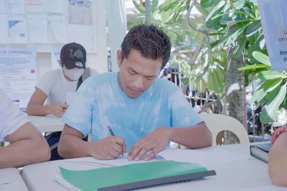 Applicants completing forms and meeting IPI recruiters at a PESO special recruitment activity held under tents in the city grounds
