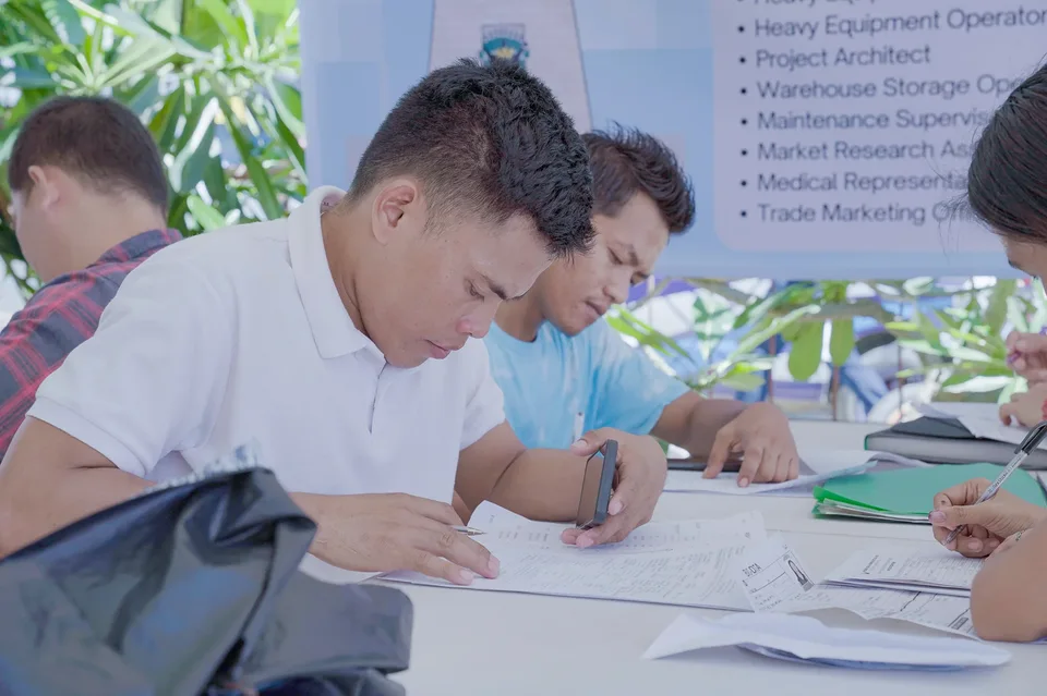 Applicants completing forms and meeting IPI recruiters at a PESO special recruitment activity held under tents in the city grounds