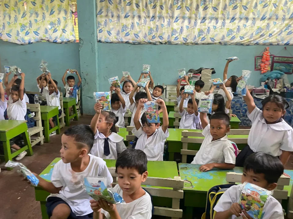 Schoolchildren in their classroom during an IPI Adopt-a-School handwashing and hygiene session, holding the hygiene kits they were given
